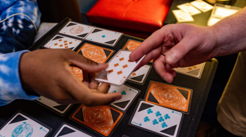 Young Adult Peer Mentor Jake Look and 16-year-old Nathanial pass cards as they play a game of Trash during a lesson at Riverside Community Care in Milford, Mass.  (Jesse Costa/WBUR)