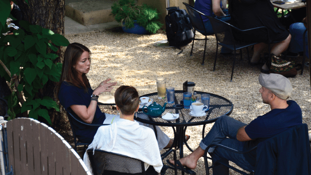 Three people chat over tea and coffee outside a restaurant in Santa Fe, New Mexico.